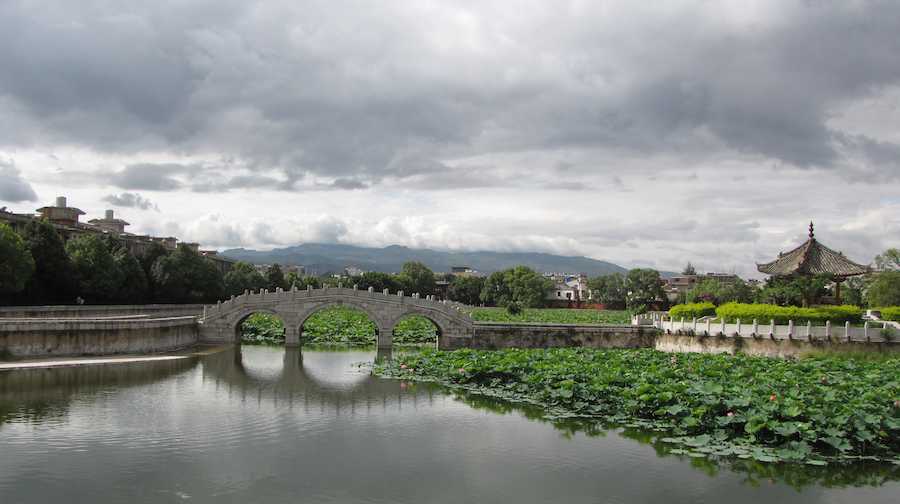photo of stone bridge over water with mountains in the background