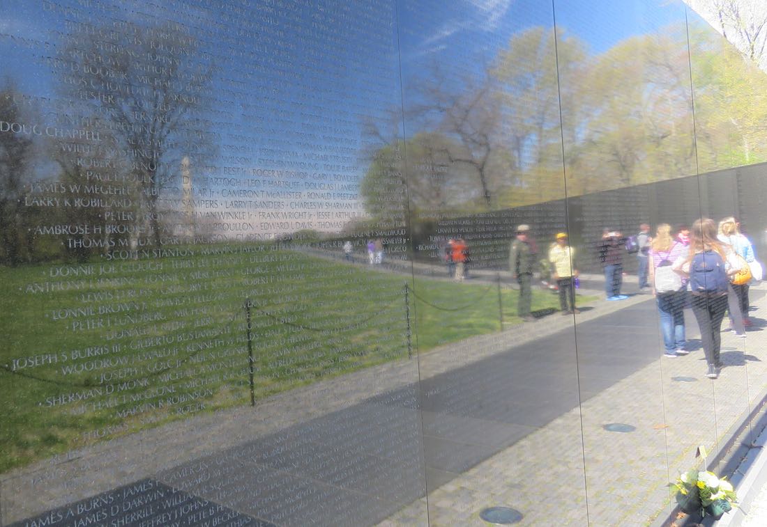Vietnam War Memorial reflecting visitors, trees and the Washington Monument